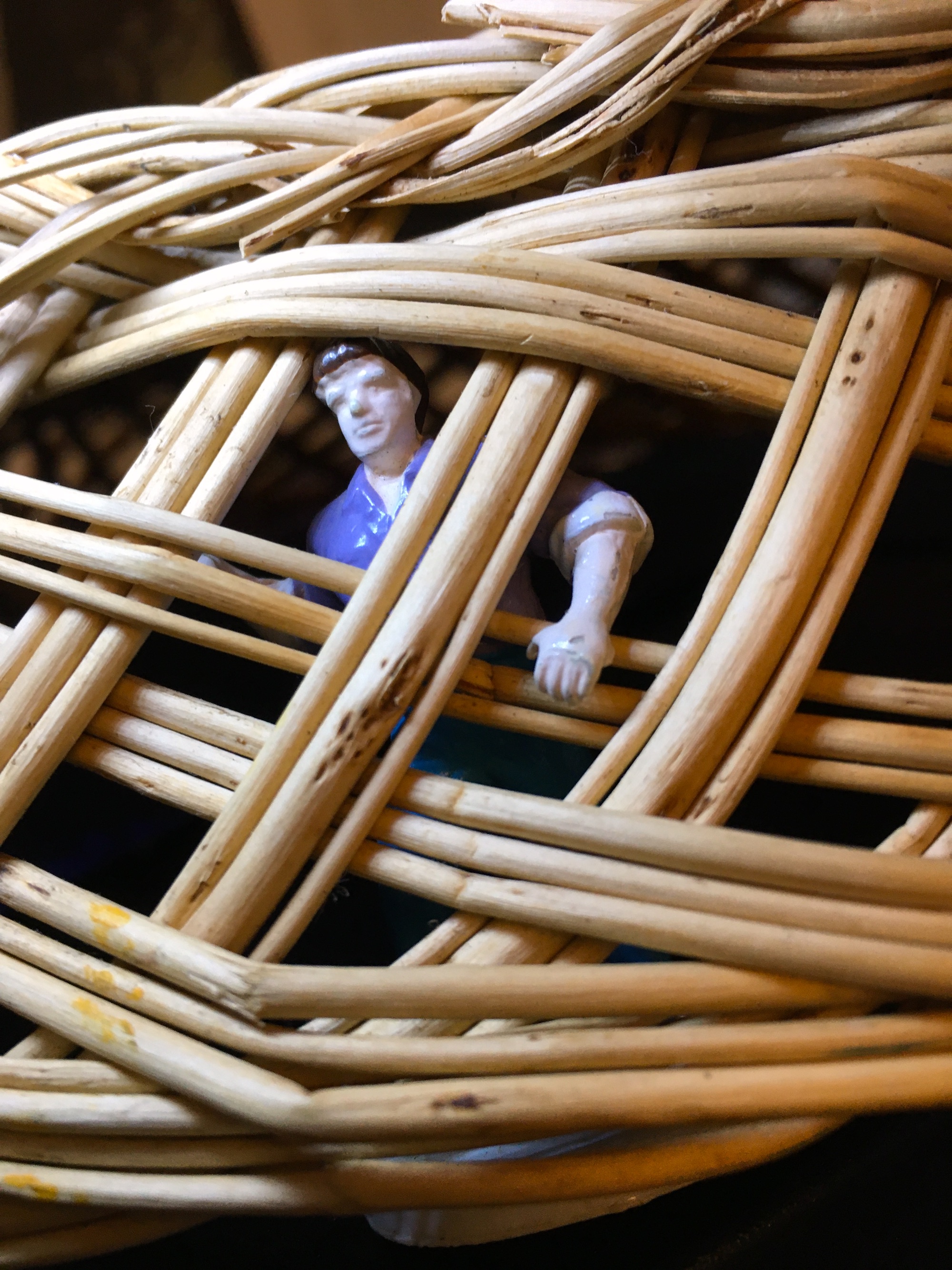 Toy man held behind a wicker cage